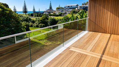 Glass balustrade on a timber deck with a coastal view