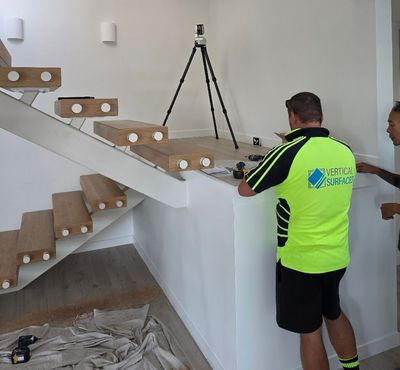 Vertical Surfaces installer in branded workwear with the digital measuring system at a floating staircase