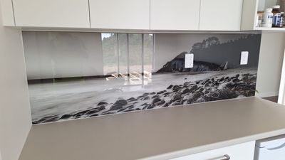 Printed glass splashback with a black and white rocky beach design