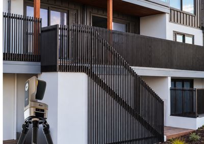 Leica iCON iCS50 measuring system set up on-site at St Patricks Row, with the completed black aluminium balustrade and staircase behind it